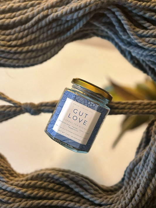 Glass jar of Gut Love herbal tea laying on mirror covered in ropes.