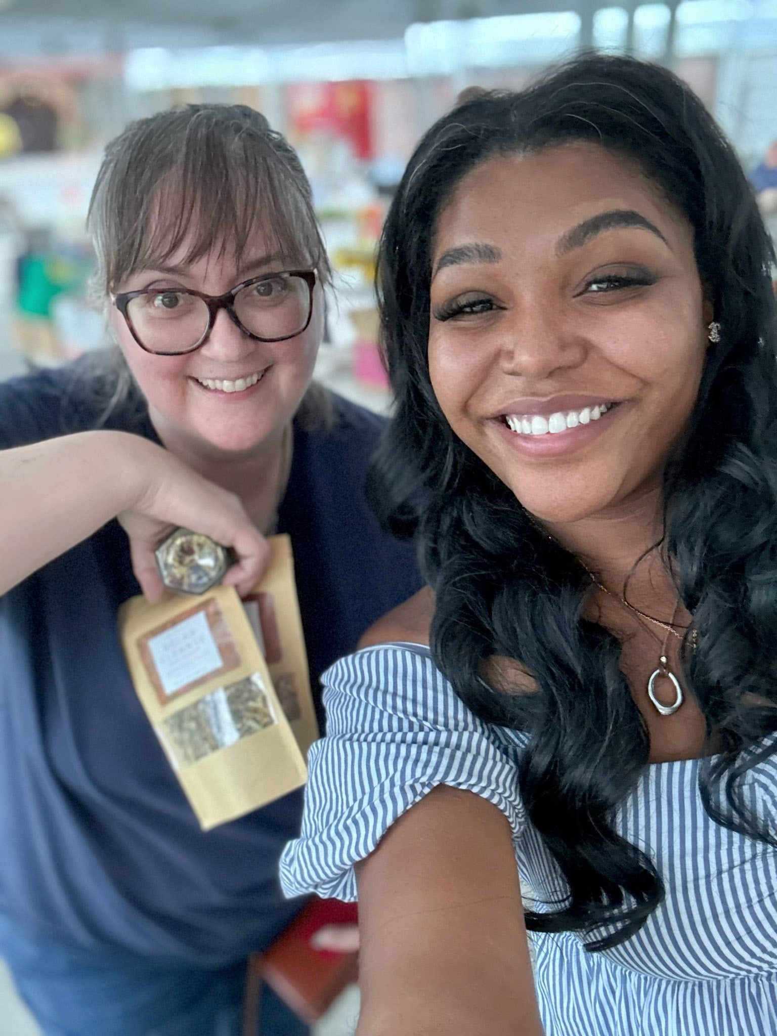 Shatice Jones and woman posing for a selfie in a market setting showing herbal tea blends manufactured by Nava Living Co..