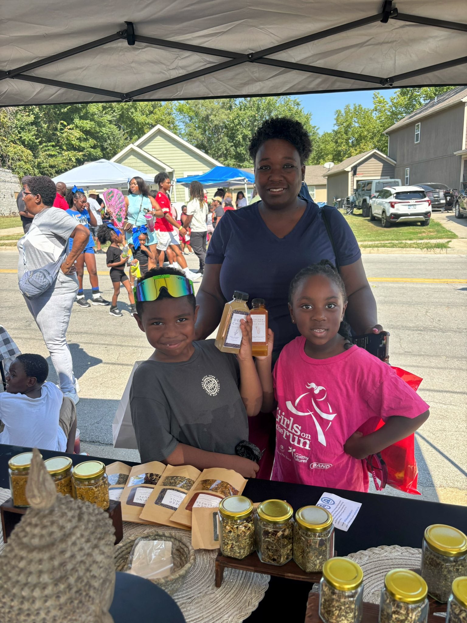 Woman and children at a street fair with Nava Living Co. loose leaf tea jars on a table