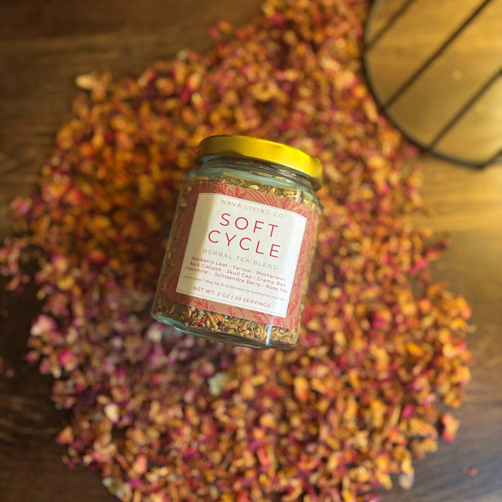 Jar of 'Soft Cycle' product surrounded by dried flowers on a wooden surface